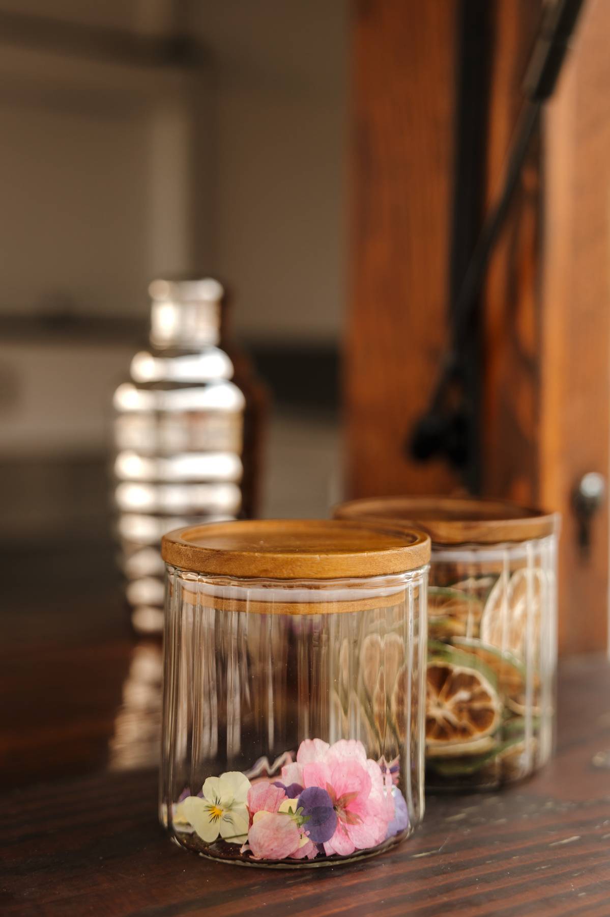 Glass jars of dried citrus and pressed flowers on the bar counter$