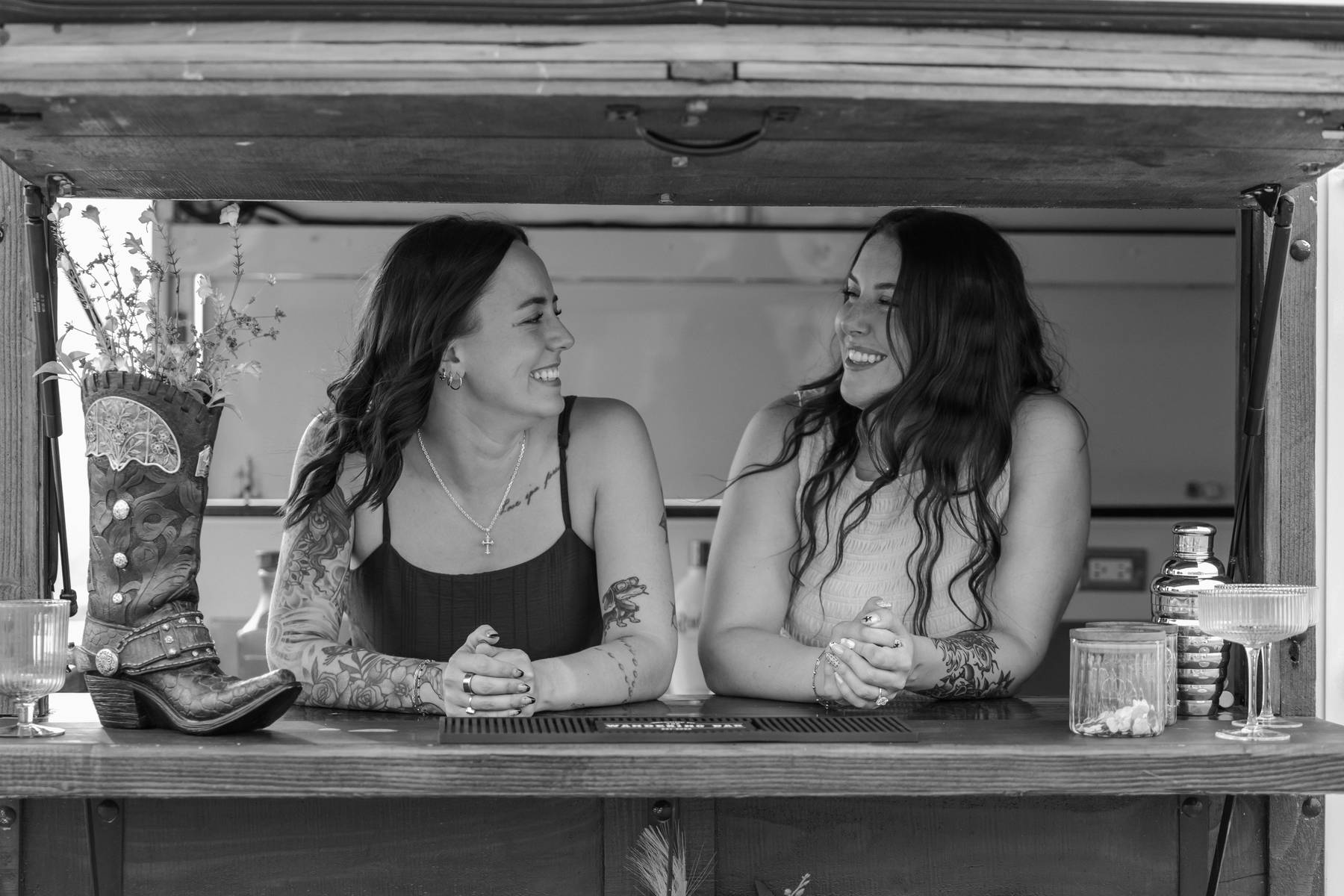 Black and white portrait of two bartenders smiling behind the trailer bar$