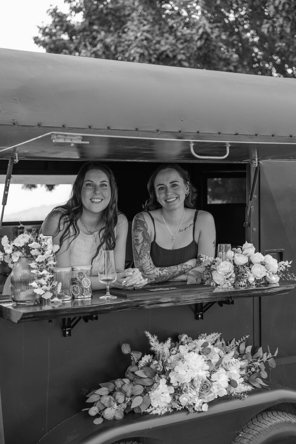 Black and white portrait of the team behind the black trailer bar with florals$