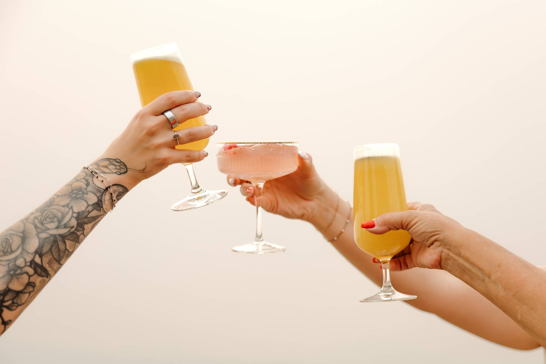Guests clinking three different cocktails in a toast$