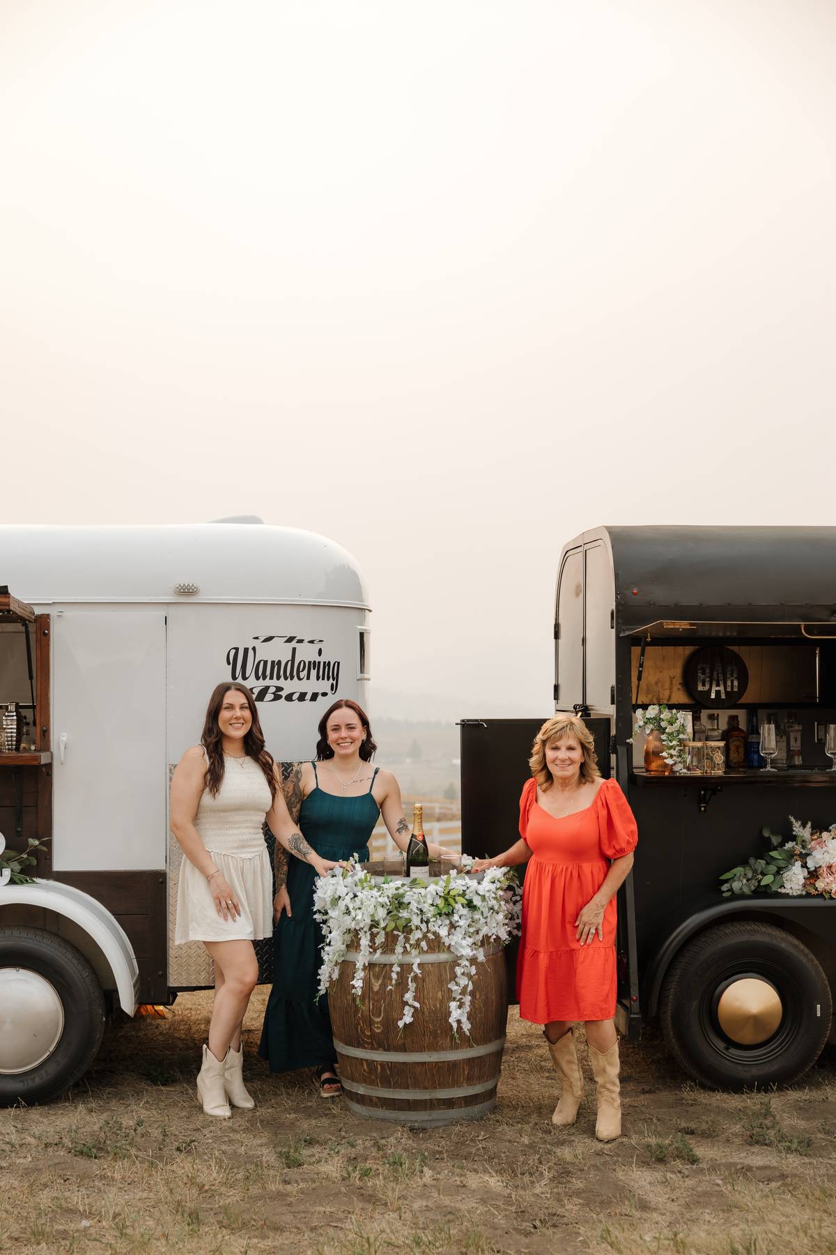The Wandering Bar team beside both trailers with a floral champagne barrel$