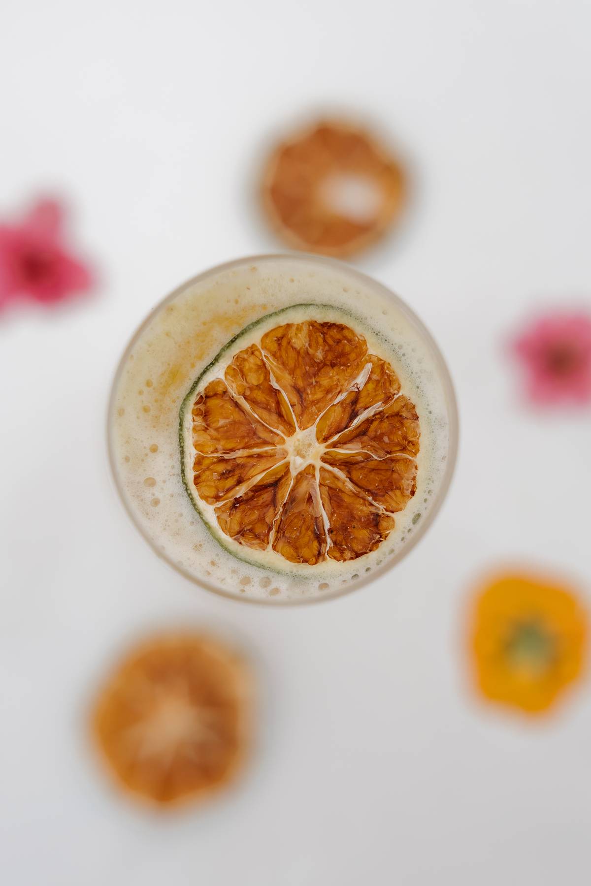 Overhead detail of a cocktail garnished with dried citrus and flowers$